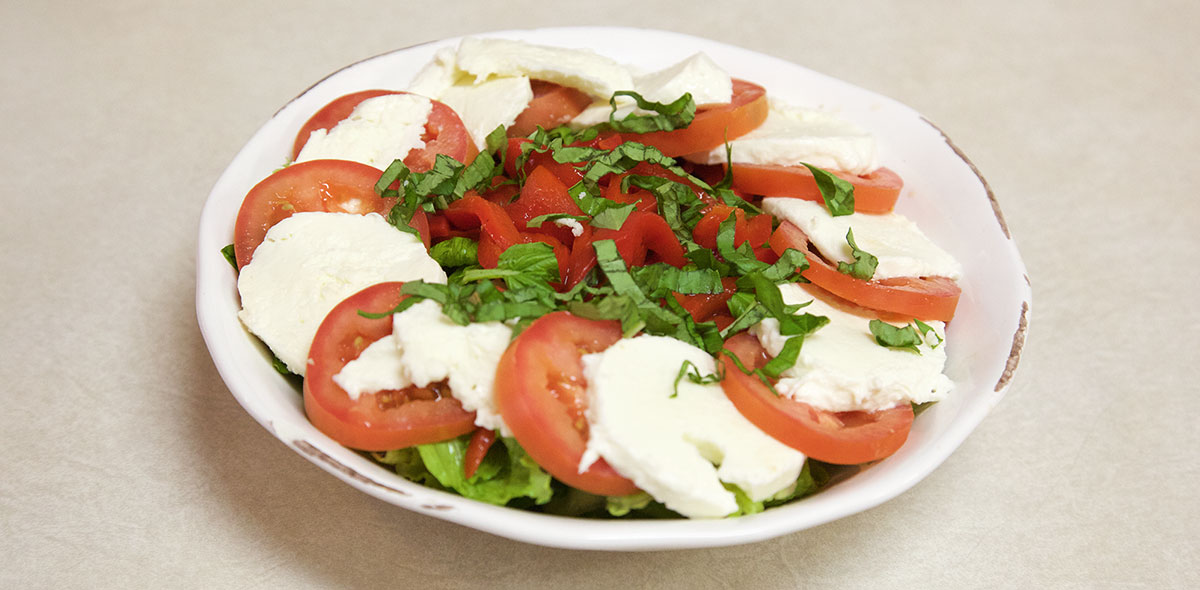 a salad with cheese and tomatoes, on a white plate