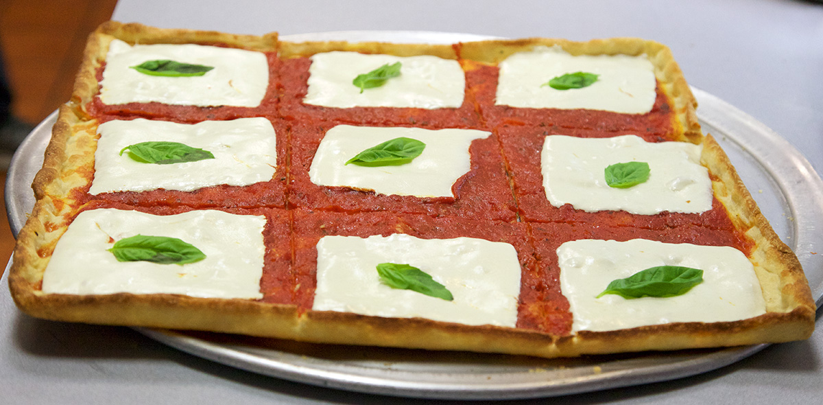 a square pizza, with square cheese, and mint leaves